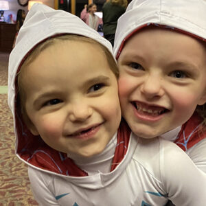 Two young girls with white hoodies smiling.