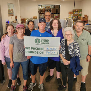 Group of people of all ages holding a sign for the Emergency Food Network.