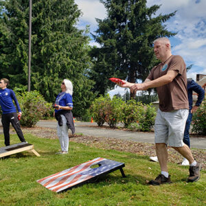 People playing cornhole outside and smiling.