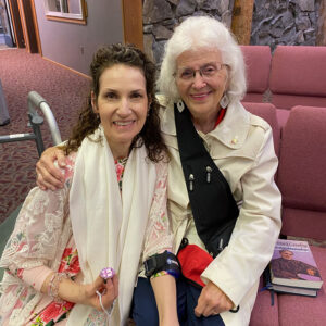 An older and younger woman sitting together in church with a bible.